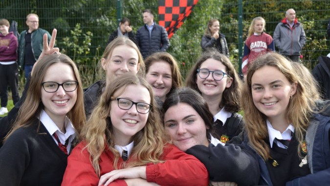 Eine Gruppe Schüler der Sutton Park School posiert draußen in Schuluniformen vor einem Zaun mit Bäumen im Hintergrund.
