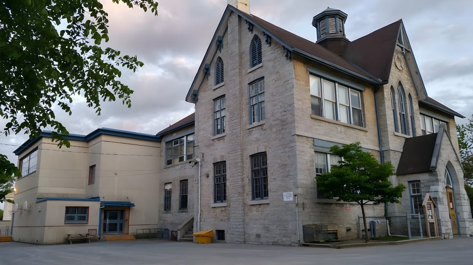 Das mehrstöckige Backsteingebäude mit einem markanten Turm gehört zur Sydenham High School und ist von Bäumen umgeben.