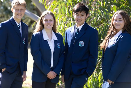 Vier Schüler stehen gemeinsam in einem natürlichen Umfeld mit Bäumen auf dem Gelände der Sylvania High School.