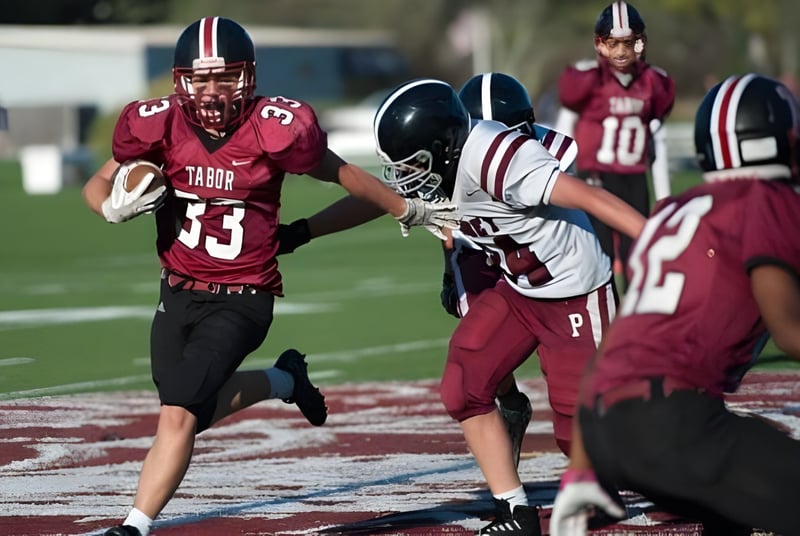 Schüler der Tabor Academy spielen ein Footballspiel auf dem Spielfeld mit roter und weißer Sportkleidung.