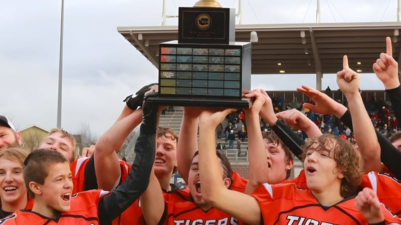 Eine Gruppe Schüler der Tacoma Public Schools feiert den Gewinn eines Pokals vor einem stadionartigen Gebäude.
