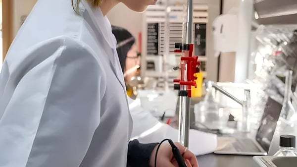 Eine Person im weißen Laborkittel steht in einem Labor der Taejon Christian International School neben wissenschaftlichen Geräten.