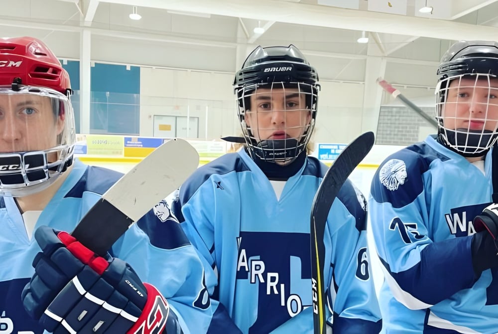 Drei Hockeyspieler in blauen Uniformen stehen in der Halle auf der Eisbahn der Tagwi Secondary School.