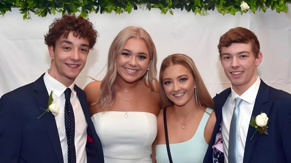 Vier Schülerinnen und Schüler des Taieri College posieren zusammen vor einem floralen Hintergrund in einem formellen Rahmen.