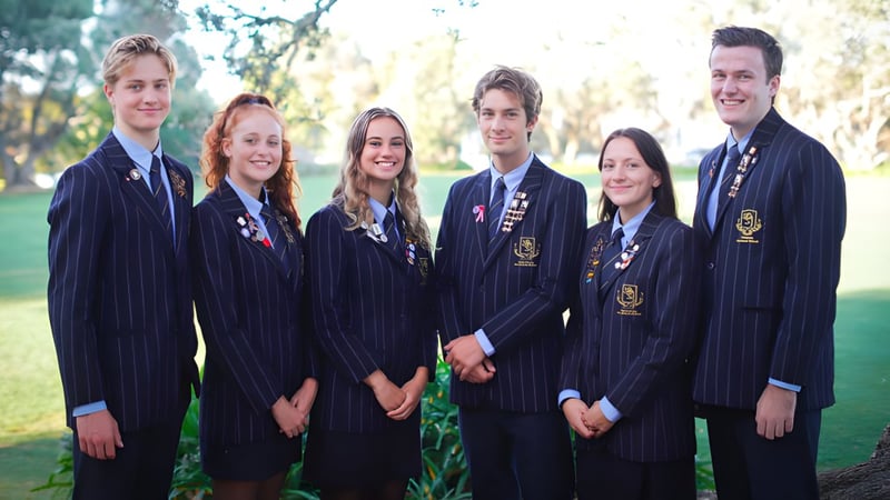 Eine Gruppe von Schülern der Takapuna Grammar School steht gemeinsam in einem parkähnlichen Bereich mit Bäumen und Grünflächen.
