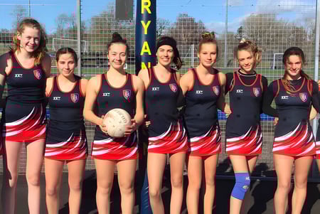 Eine Gruppe junger Sportlerinnen der Talbot Heath School steht mit einem Rugbyball auf dem Sportplatz.