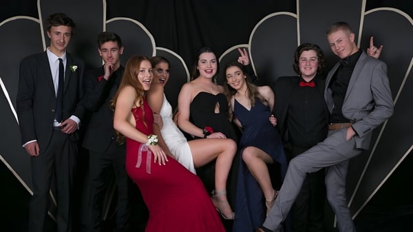 Eine Gruppe von Personen in formeller Kleidung posiert vor einem abstrakten Hintergrund auf dem Campus der Taradale High School.