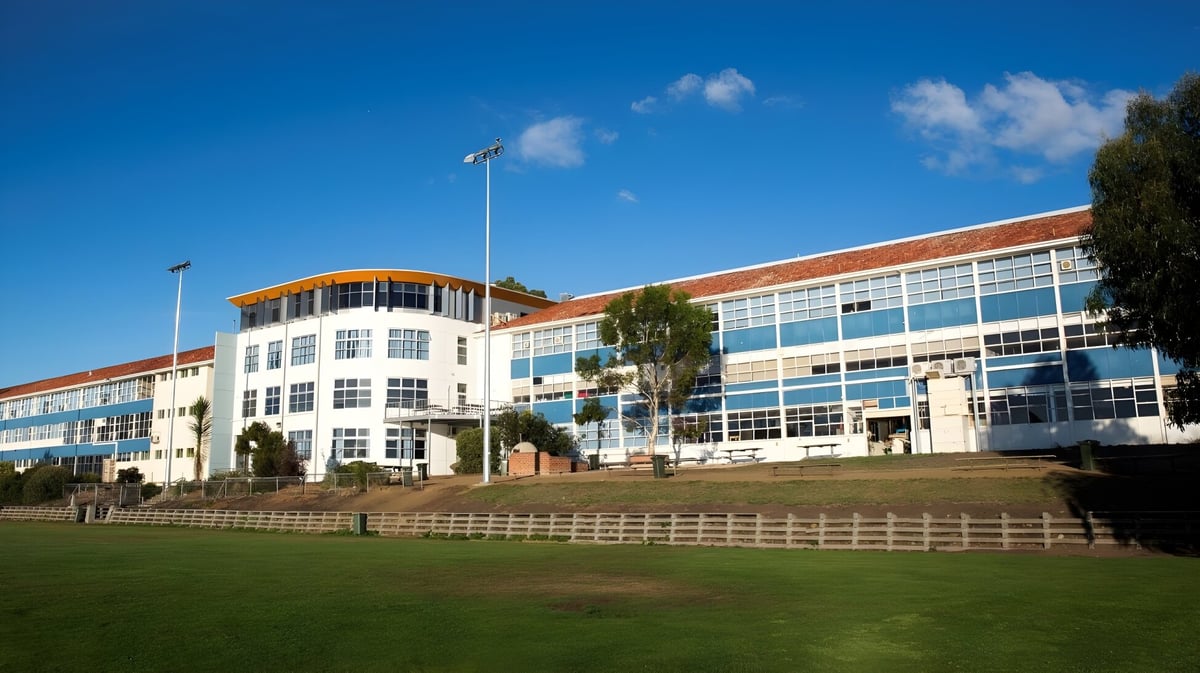 Das mehrstöckige Gebäude der Taroona High School zeigt moderne Glas- und Backsteinfassaden vor blauem Himmel.