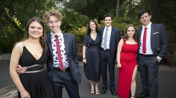 Eine Gruppe gut gekleideter Personen posiert gemeinsam in einer grünen Außenanlage der Taroona High School.