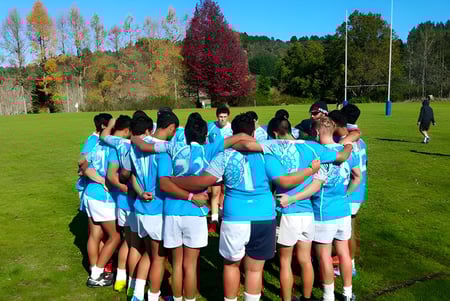 Schüler der Taumarunui High School versammeln sich auf einer Wiese vor buntem herbstlichem Laub.