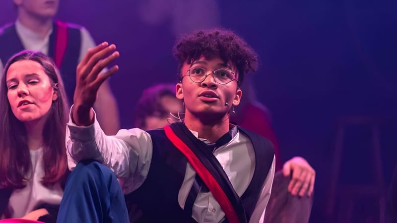 Ein Schüler der Taunton School International steht auf einer Bühne und gestikuliert ausdrucksstark während einer Aufführung.