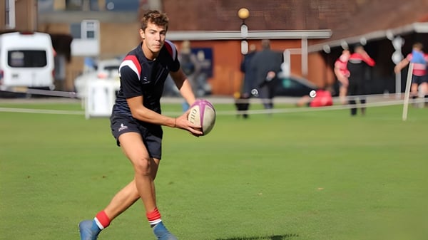 Ein junger Schüler der Taunton School hält auf dem Sportfeld einen Rugbyball in der Hand.