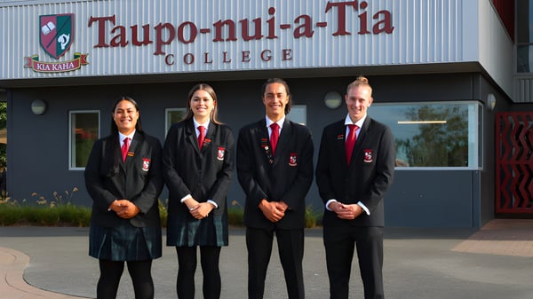 Vier Personen in formeller Kleidung stehen vor dem Gebäude des Taupo-nui-a-Tia College.