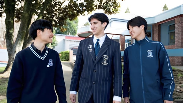 Drei Schüler in Schuluniform stehen gemeinsam auf dem Schulhof des Tauranga Boy's College.
