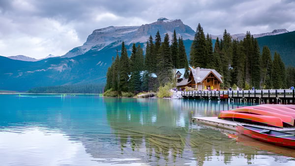 Ein ruhiger alpiner See mit buchtenfarbenen Kanus an einem Holzsteg, umgeben von Bergen und Kiefernwäldern, nahe der Technical Vocational High School.
