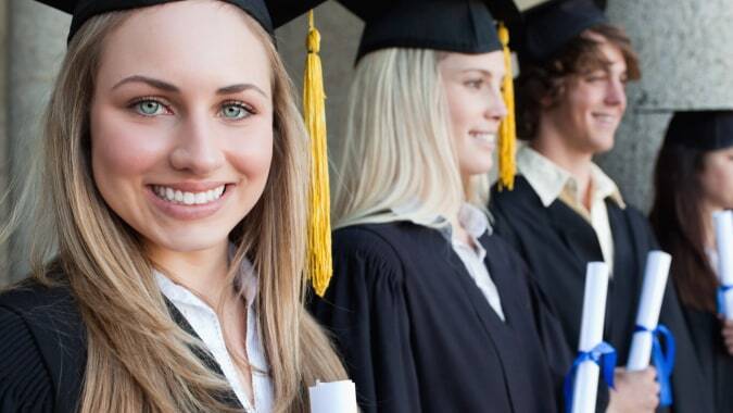 Absolventen des Templemichael College in schwarzen Talaren stehen gemeinsam vor einem Gebäude.