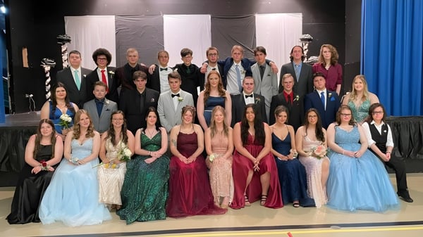 Eine große Gruppe von Schülerinnen und Schülern der Templeton Academy steht auf einer Bühne vor schwarzem Hintergrund und blauen Vorhängen.