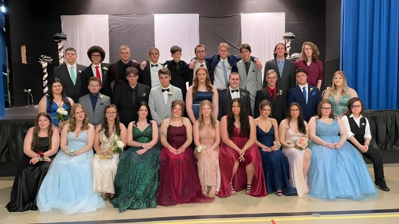 Eine große Gruppe von Schülerinnen und Schülern der Templeton Academy steht auf einer Bühne vor schwarzem Hintergrund und blauen Vorhängen.