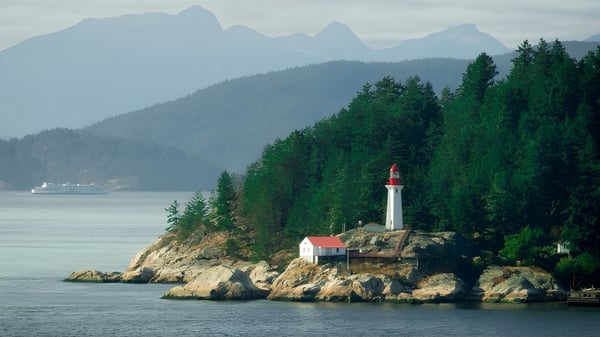 Ein Leuchtturm auf einem felsigen Küstenabschnitt mit Wäldern und Bergen im Hintergrund auf dem Gelände der Templeton Secondary School.