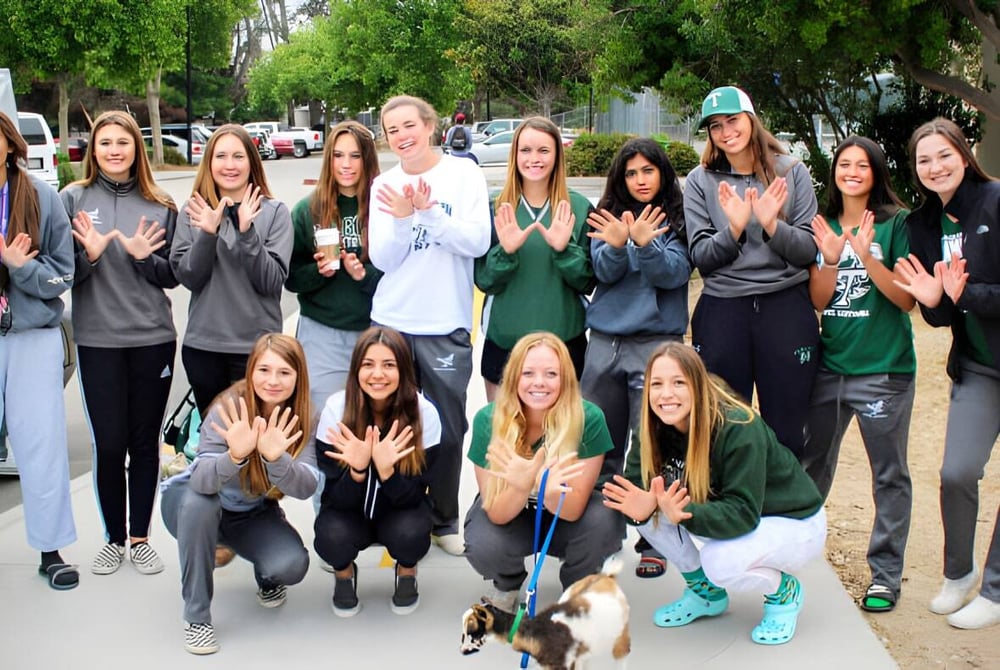 Eine Gruppe Schülerinnen der Templeton Secondary School posiert draußen vor Bäumen und Gebäuden für ein Foto.