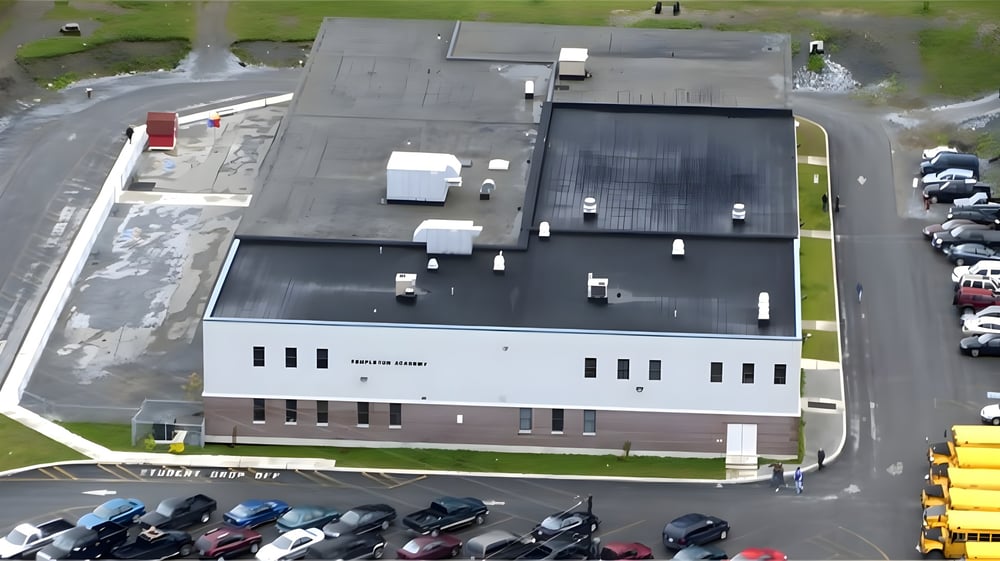 Das große Industriegebäude der Templeton Academy ist von einem Parkplatz und einer Grünfläche umgeben.