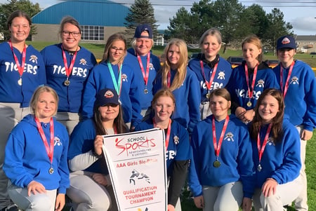 Eine Gruppe Schülerinnen der Templeton Academy steht in blauen Uniformen mit Medaillen und Pokal vor einem Sportgebäude.