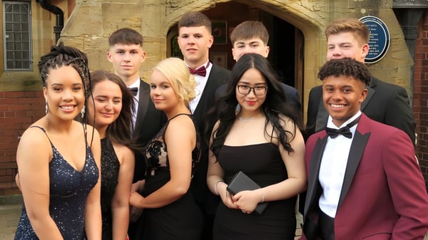 Eine Gruppe Schüler des Tettenhall College posiert in formeller Kleidung vor einem historischen Gebäude mit Rundbögen.