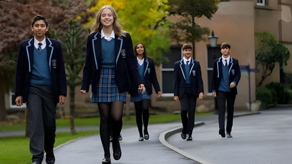 Eine Gruppe Schüler in Schuluniformen geht gemeinsam auf einem von Grün umgebenen Weg auf dem Campus des Tettenhall College.