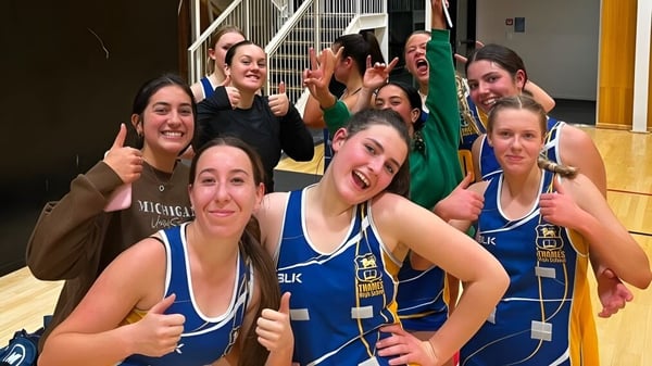 Eine Gruppe von Schülerinnen und Schülern der Thames High School posiert in blauen Sportuniformen in einer Sporthalle.