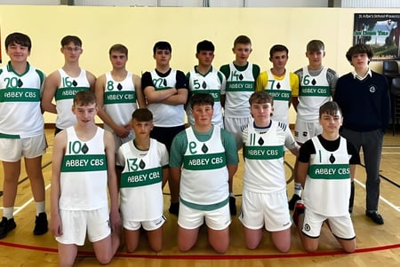 Eine Gruppe von Schülern der The Abbey School posiert gemeinsam in der Sporthalle als Basketballteam.