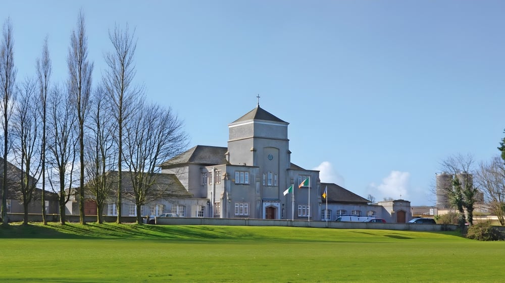 Das historische Gebäude mit einem hohen Turm und einer grünen Wiese im Vordergrund befindet sich auf dem Campus der The Abbey School.