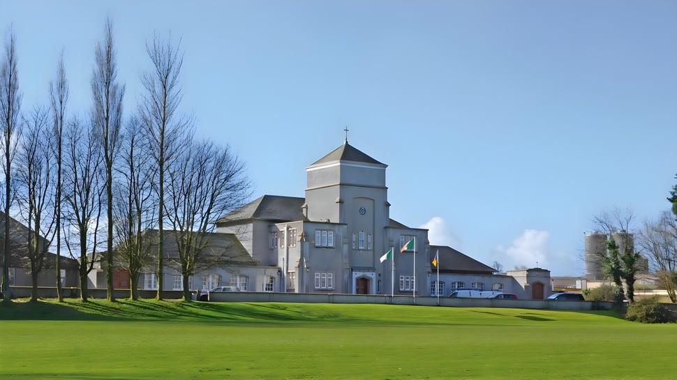 Das historische Hauptgebäude der The Abbey School steht vor einem grünen Rasen mit kahlen Bäumen im Hintergrund.
