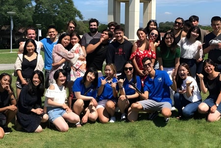 Eine große Gruppe junger Menschen versammelt sich auf einer Wiese auf dem Campus der The Academy MiraCosta.