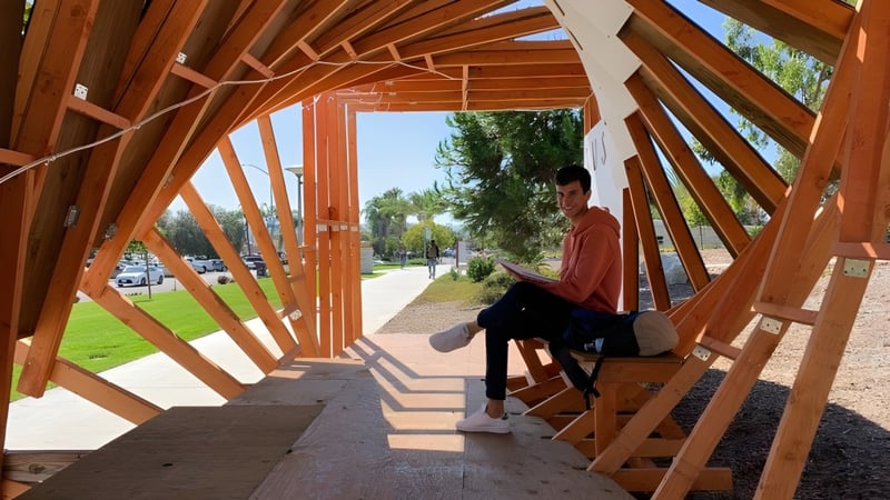 Eine Person sitzt auf einer Bank am Holzweg mit geometrischem Muster auf dem Campus der The Academy MiraCosta.