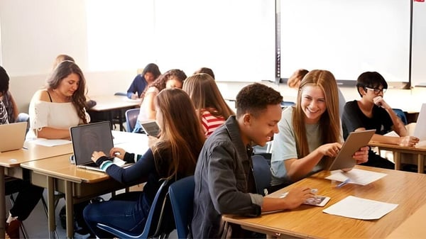 Eine Gruppe Schülerinnen und Schüler der The Barnes Academy sitzt in einem Klassenzimmer und arbeitet gemeinsam an verschiedenen Aufgaben.