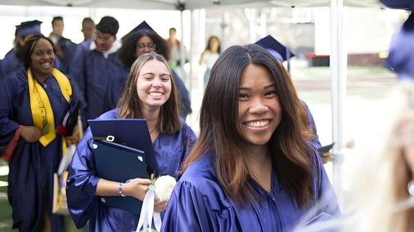 Eine Gruppe von Absolventinnen und Absolventen der The Beekman School feiert gemeinsam ihre Graduierung in blauen Talaren.