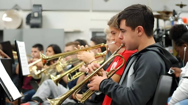 Schüler der The Beekman School spielen Blechblasinstrumente vor musikalischem Equipment.