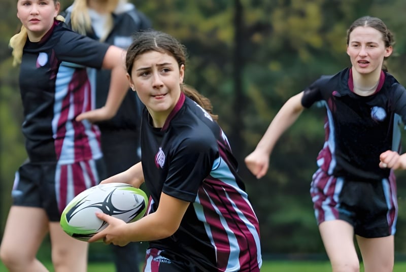 Schülerinnen der The Bishop Strachan School spielen Fußball auf einem Rasenfeld mit Bäumen im Hintergrund.