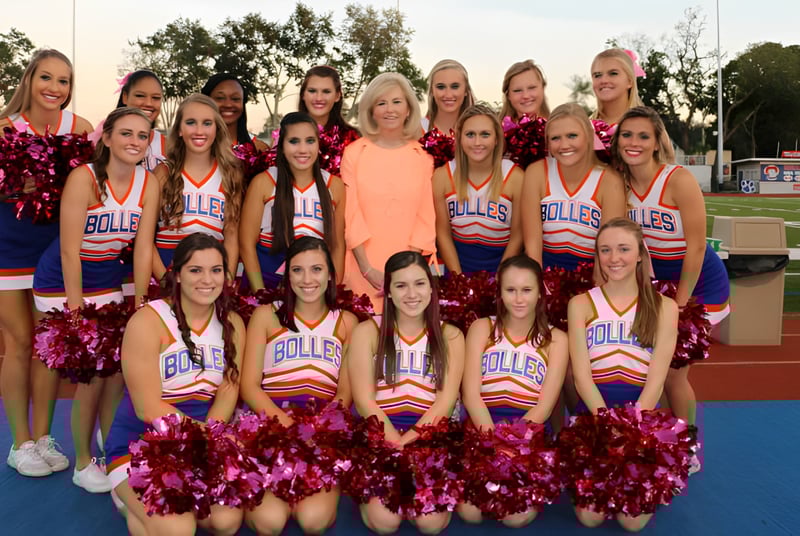 Eine Gruppe Cheerleader steht auf dem Sportfeld der The Bolles School mit einheitlichen Uniformen und Pompons.