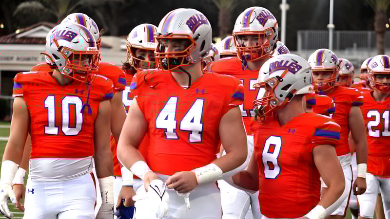 Eine Fußballmannschaft der The Bolles School steht gemeinsam auf dem Spielfeld mit einem Stadion im Hintergrund.