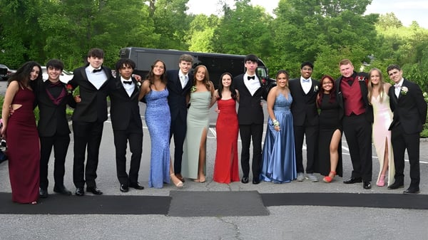 Eine Gruppe elegant gekleideter Personen steht gemeinsam im Grünen auf dem Campus der The Bolles School.