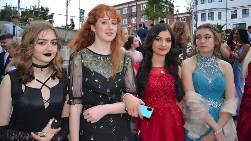 Eine Gruppe Schülerinnen der The Bourne Academy posiert in bunten Kleidern auf einer Straße in der Stadt mit Gebäuden im Hintergrund.