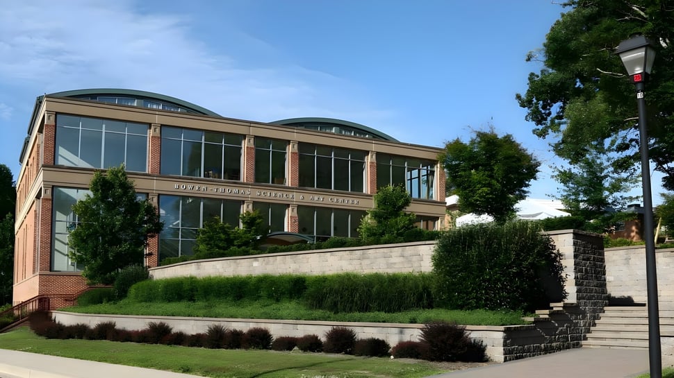 Das moderne Hauptgebäude der The Calverton School mit großen Fenstern und umliegender grüner Landschaft.