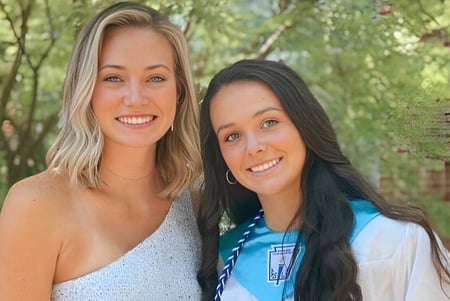 Zwei lächelnde Schülerinnen stehen zusammen im grünen Außenbereich der The Calverton School.