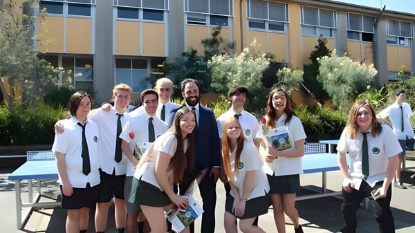 Eine Gruppe Schüler steht vor einem Gebäude mit großen Fenstern auf dem Campus der The Forest High School.