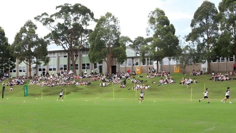 Schüler der The Forest High School spielen auf dem Sportplatz, umgeben von Bäumen und Schulgebäuden.