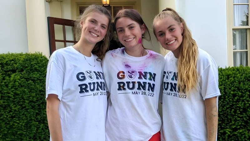 Drei Schülerinnen der The Frederick Gunn School posieren zusammen vor einem Gebäude mit einer grünen Hecke.