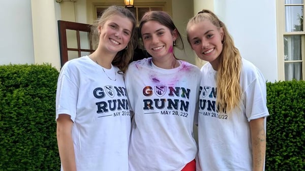 Drei Schülerinnen der The Frederick Gunn School posieren zusammen vor einem Gebäude mit grüner Hecke.