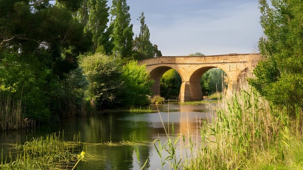 Eine malerische Steinbrücke überquert einen ruhigen Fluss auf dem Gelände der The Gap State High School.
