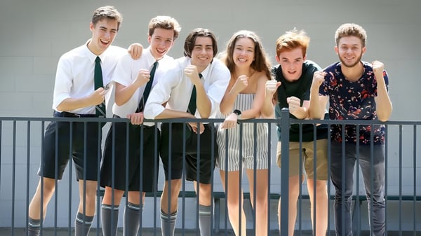 Eine Gruppe Schülerinnen und Schüler der The Gap State High School steht vor grauem Hintergrund und lächelt in die Kamera.